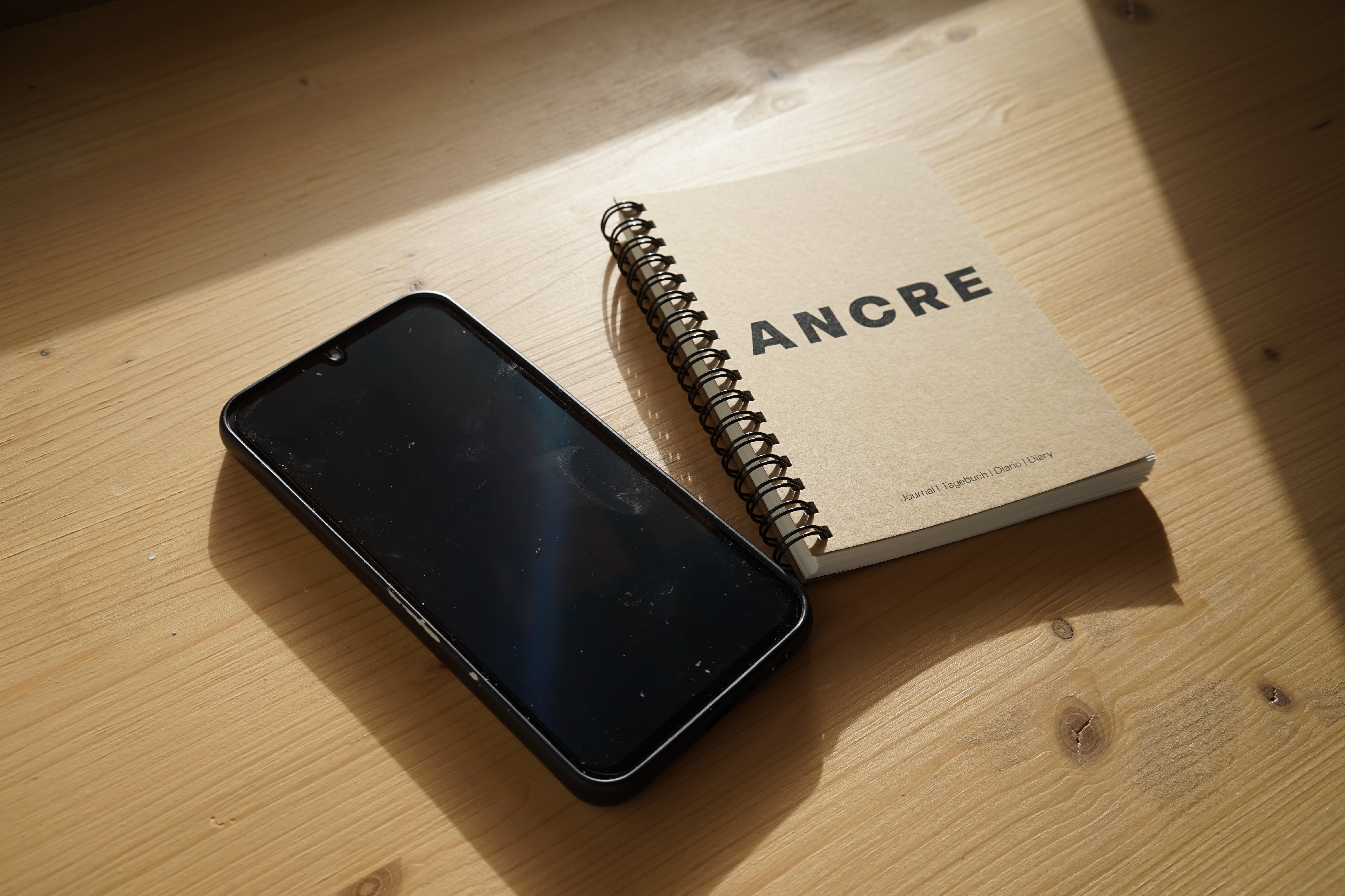Photographie d'un carnet Ancre à côté d'un téléphone portable