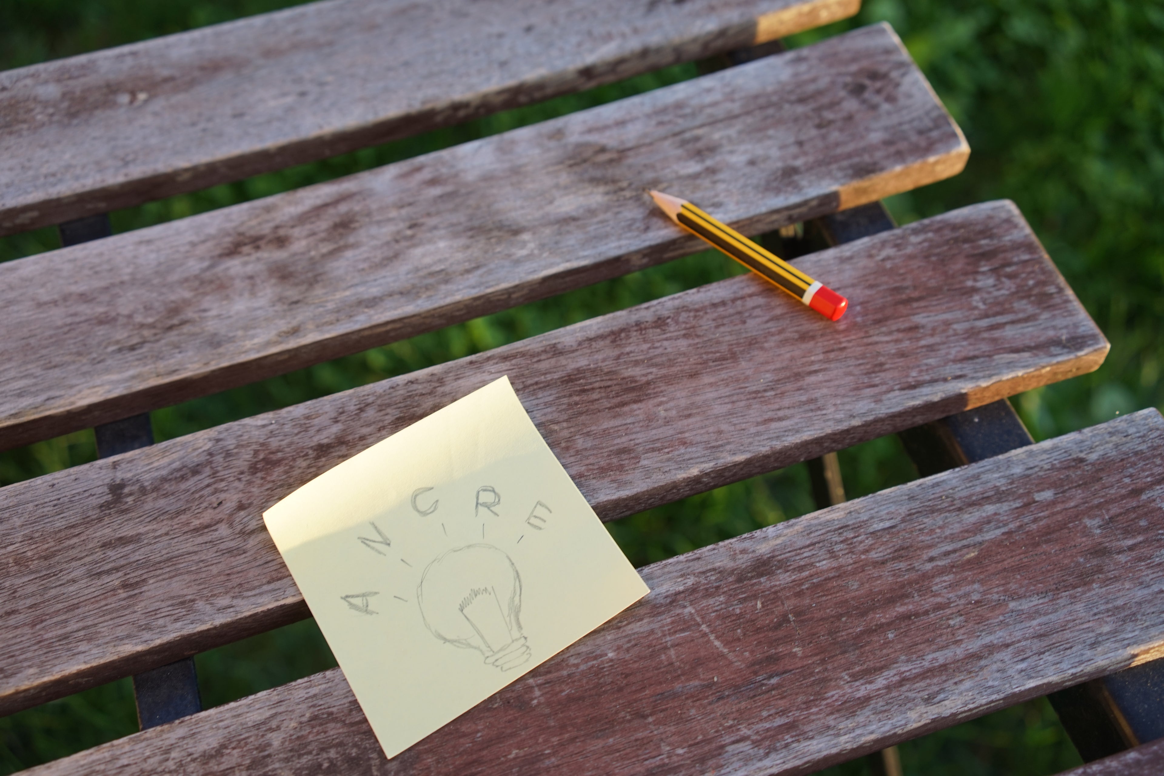 Post-it avec l'idée d'Ancre posé sur une table en extérieur avec un crayon à papier